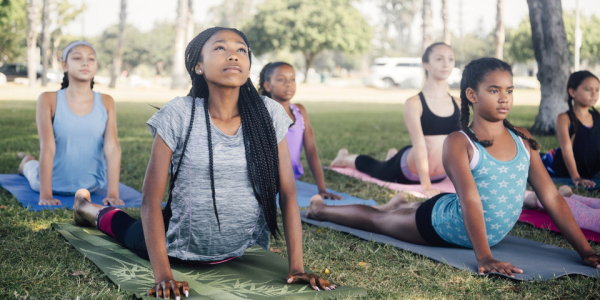 Verschiedene Teilnehmer des YES!-Programms üben Yoga-Techniken während des Führungstrainings