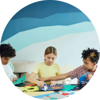 Tres niños haciendo manualidades en una mesa, fomentando la creatividad y la concentración.