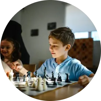 Young boy in blue shirt playing chess, focused on developing strategic thinking skills.