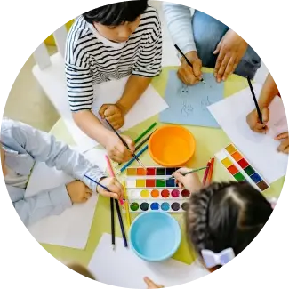 Children drawing and painting at a table, representing The Art of Living’s ART Excel life skills.