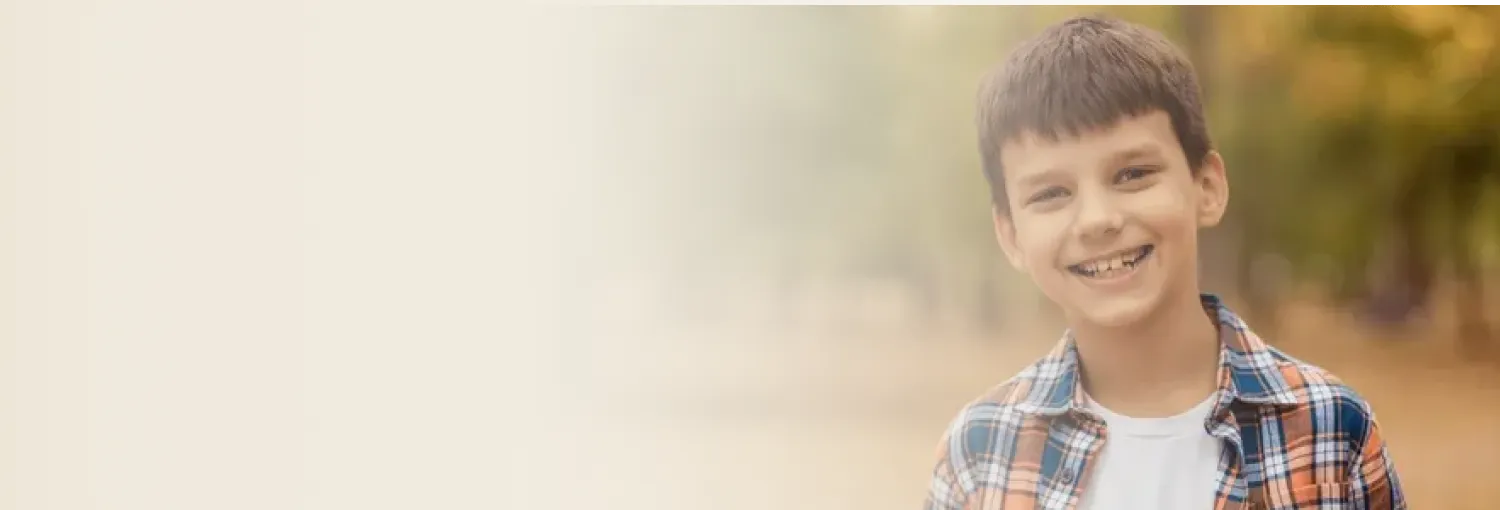 Young boy smiling gently, wearing a checkered shirt.