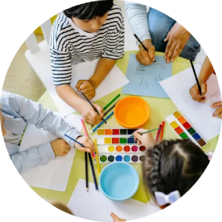 Children drawing and painting at a table, representing The Art of Living’s ART Excel life skills.