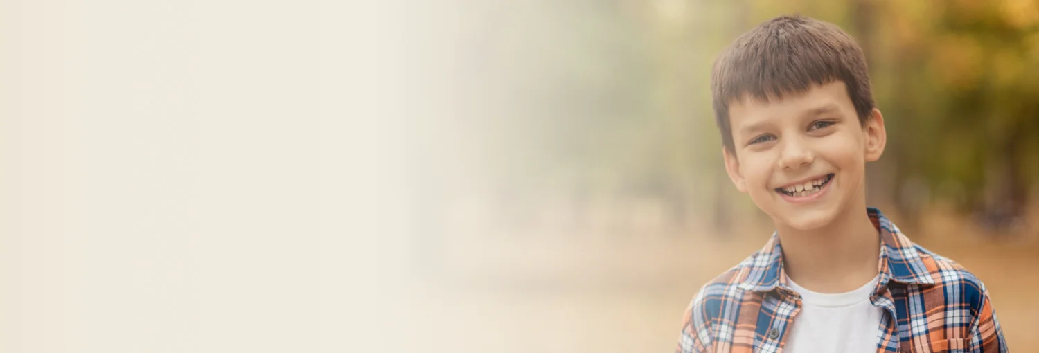 Young boy smiling gently, wearing a checkered shirt.