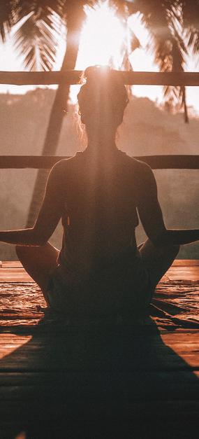 A lady meditating facing sunrise