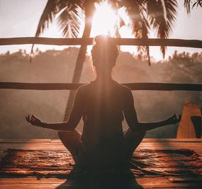 A lady meditating facing sunrise