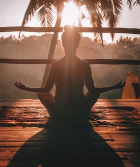 A lady meditating facing sunrise