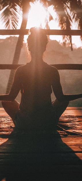 A lady meditating facing sunrise