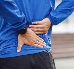 A Man keeping both the hands on lower back due to pain