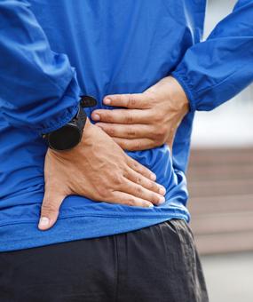 A Man keeping both the hands on lower back due to pain