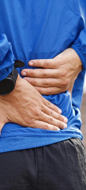 A Man keeping both the hands on lower back due to pain