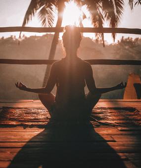 A lady meditating facing sunrise