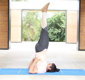 Yoga Sarvangasana - a girl lying on floor with her back stretched upwards