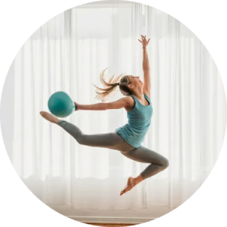 Woman leaping with a blue exercise ball overhead, showcasing a dynamic, confident pose.