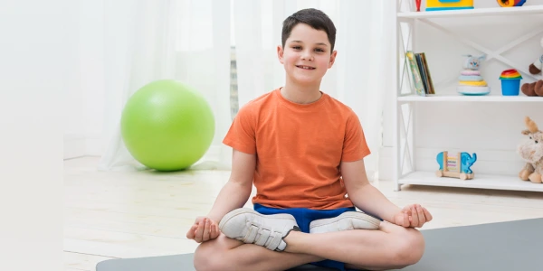 Jeune participante pratiquant la posture de méditation pendant une séance d'ART EXCEL dans un espace d'apprentissage en pleine conscience.