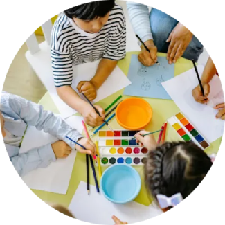 Children drawing and painting at a table, representing The Art of Living’s ART Excel life skills.